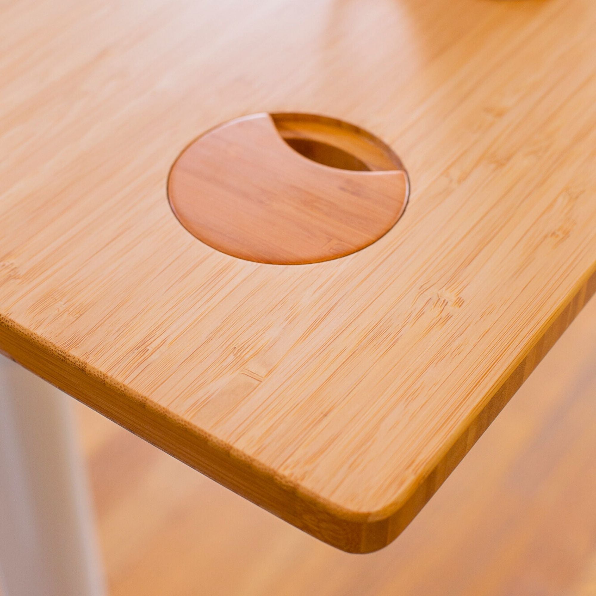 Détail du plateau bois avec passe-câble intégré sur un bureau assis debout, finition et angles arrondis