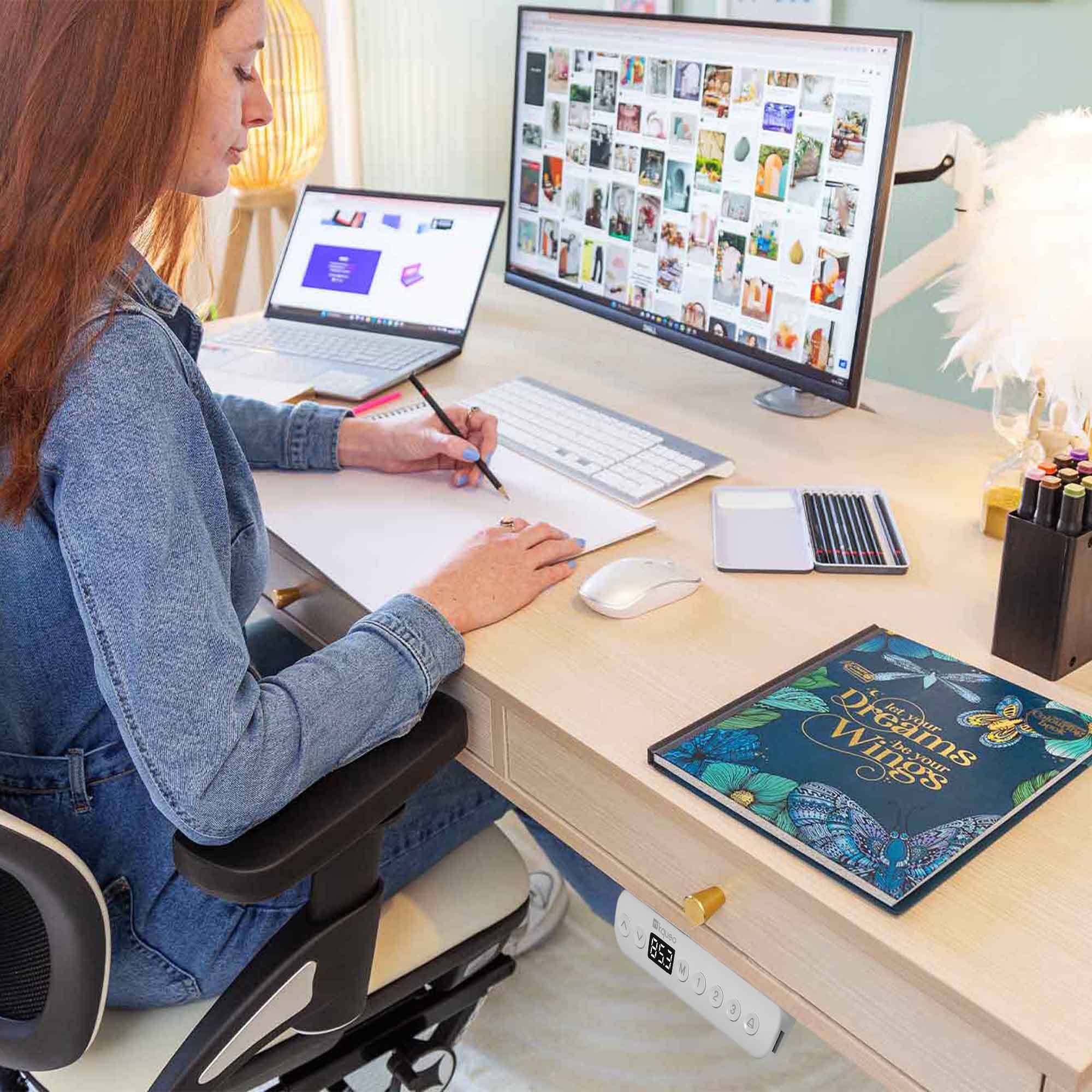 Femme assise travaillant sur un bureau assis-debout KQUEO Space Dynamique en bois très clair avec 3 tiroirs et pieds blancs.