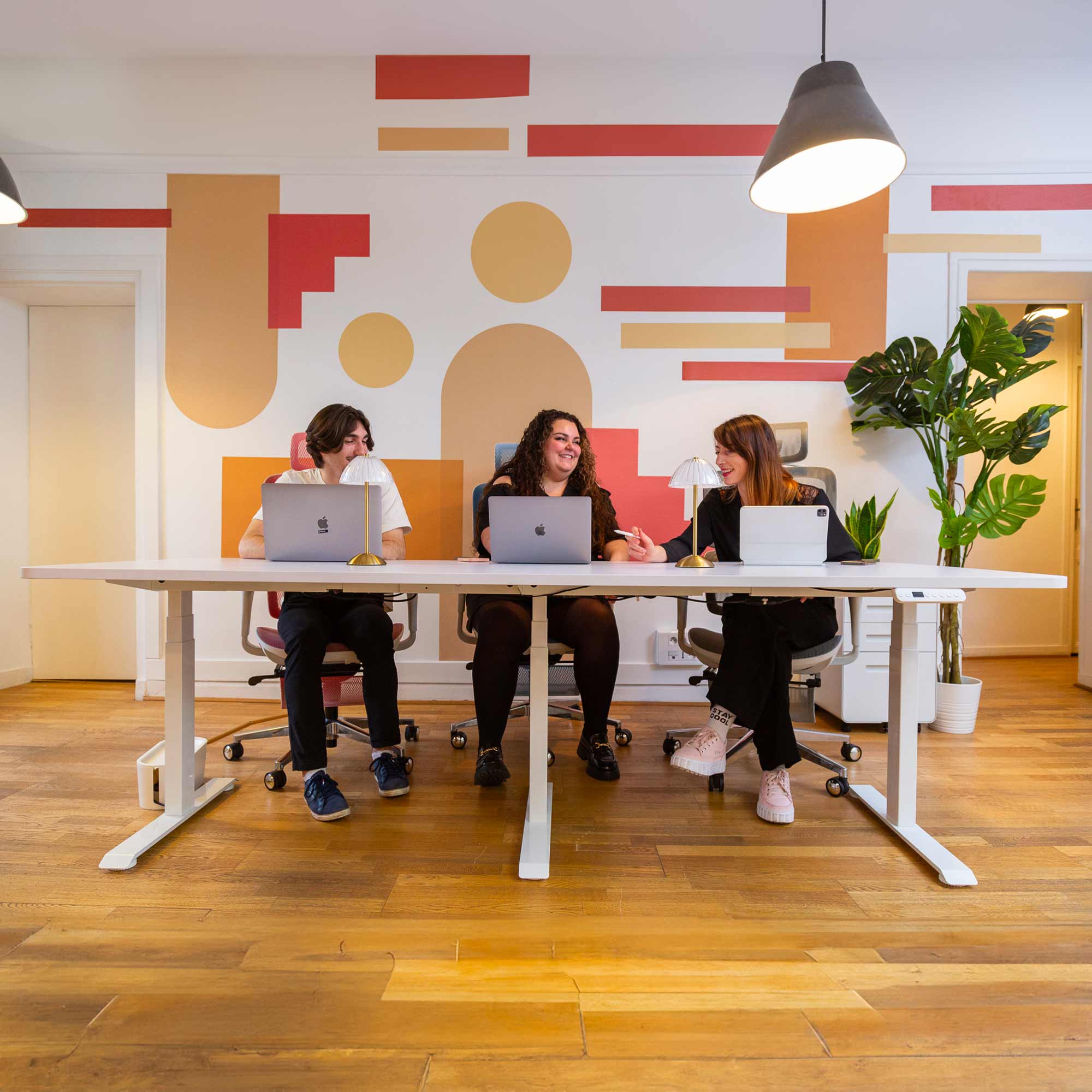 Équipe travaillant sur un bureau assis debout blanc réglable en hauteur dans un espace de travail moderne
